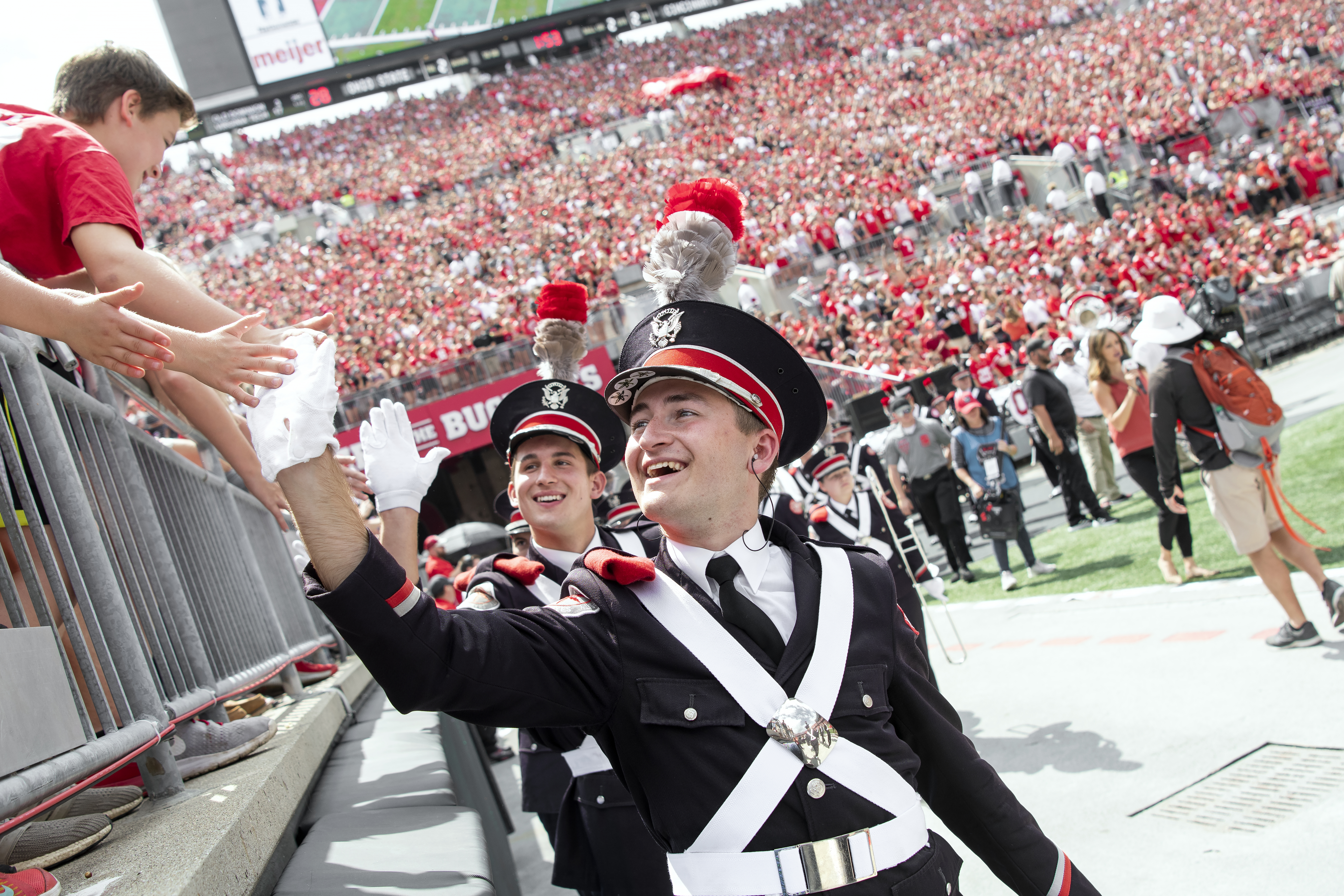 A marching band member high-fives a crowd