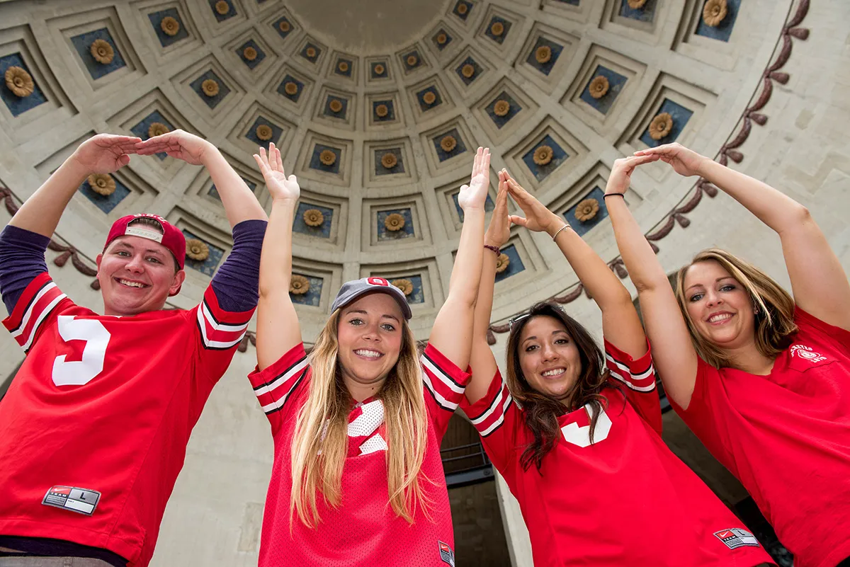 Four students in Ohio State football jerseys perform O-H-I-O in the Ohio Stadium rotunda.