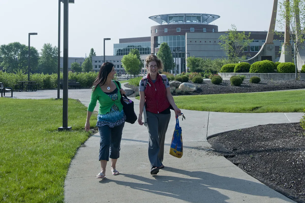 Two students walk together at Ohio State Marion with the Library Classroom Building visible in the distance.