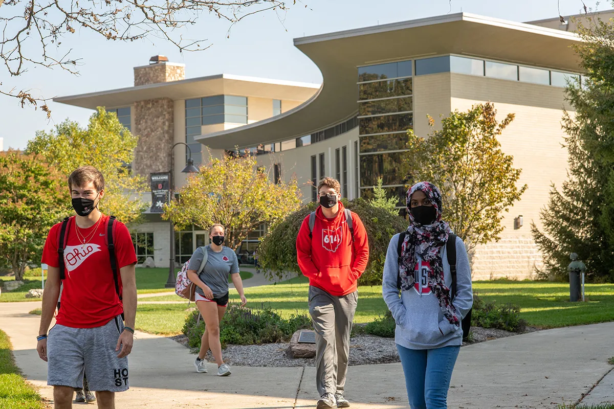 Four masked students walk on campus at Ohio State Newark.